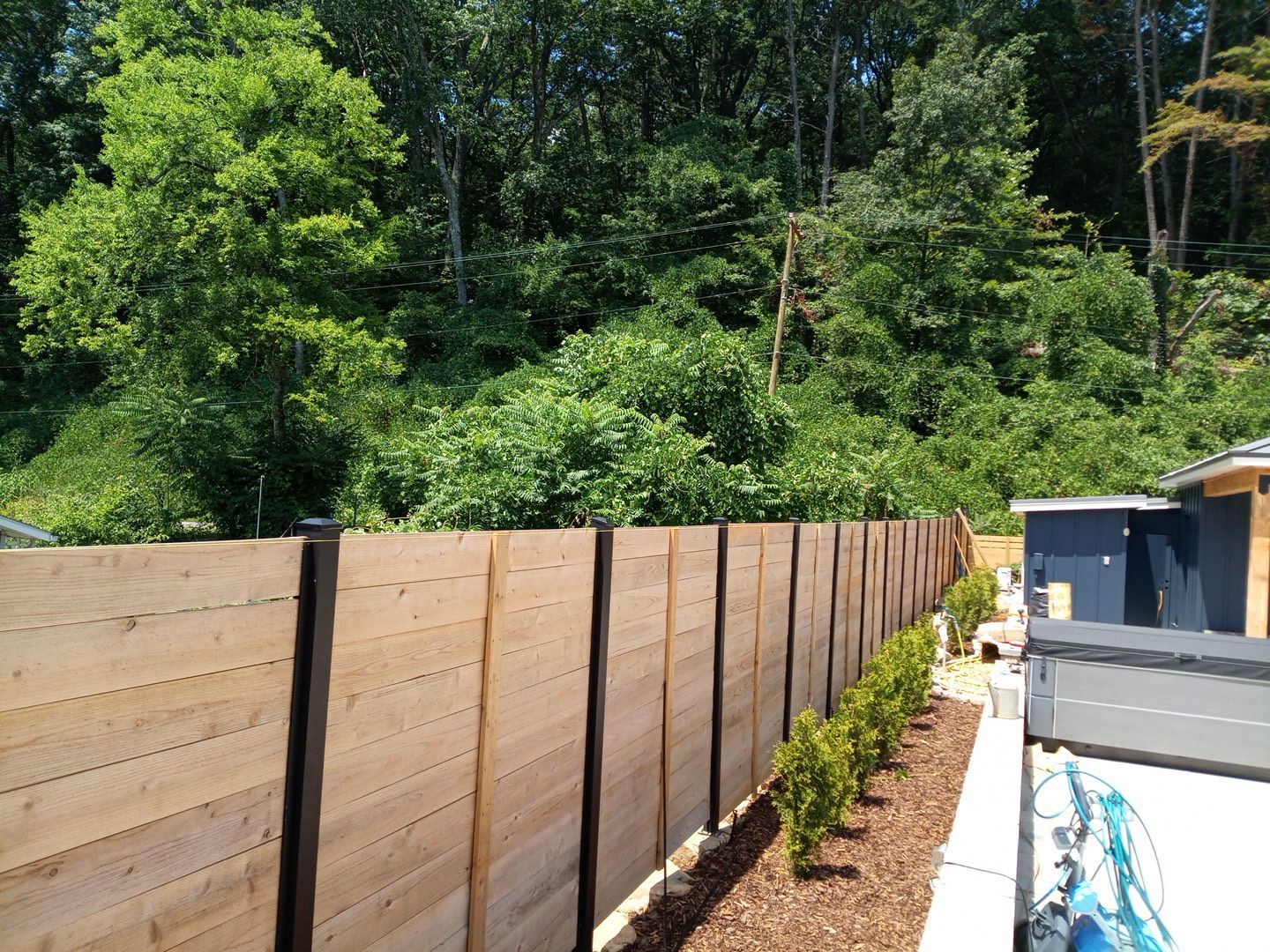 A wooden fence surrounds a house with trees in the background
