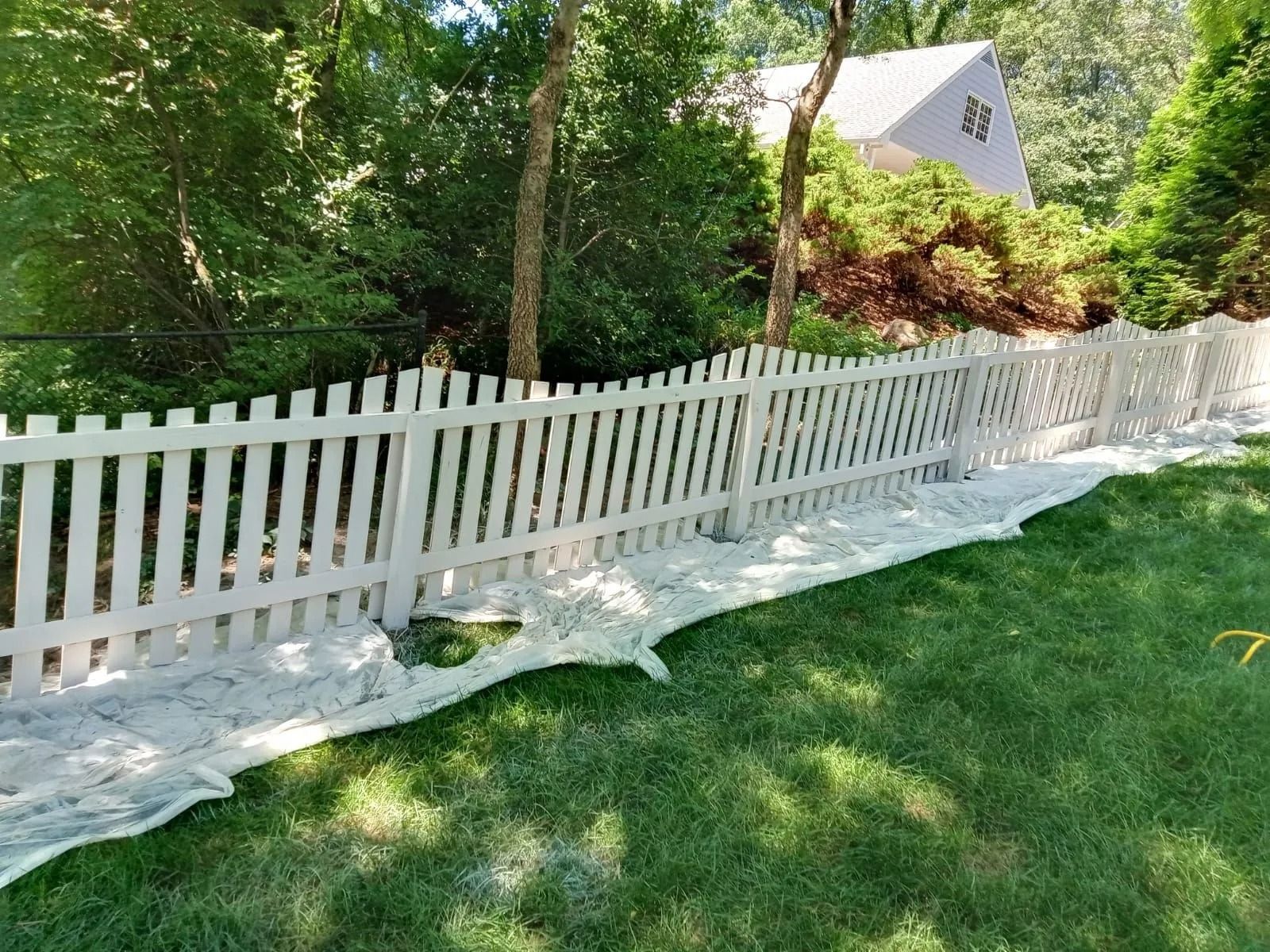 A white picket fence is sitting on top of a lush green lawn.