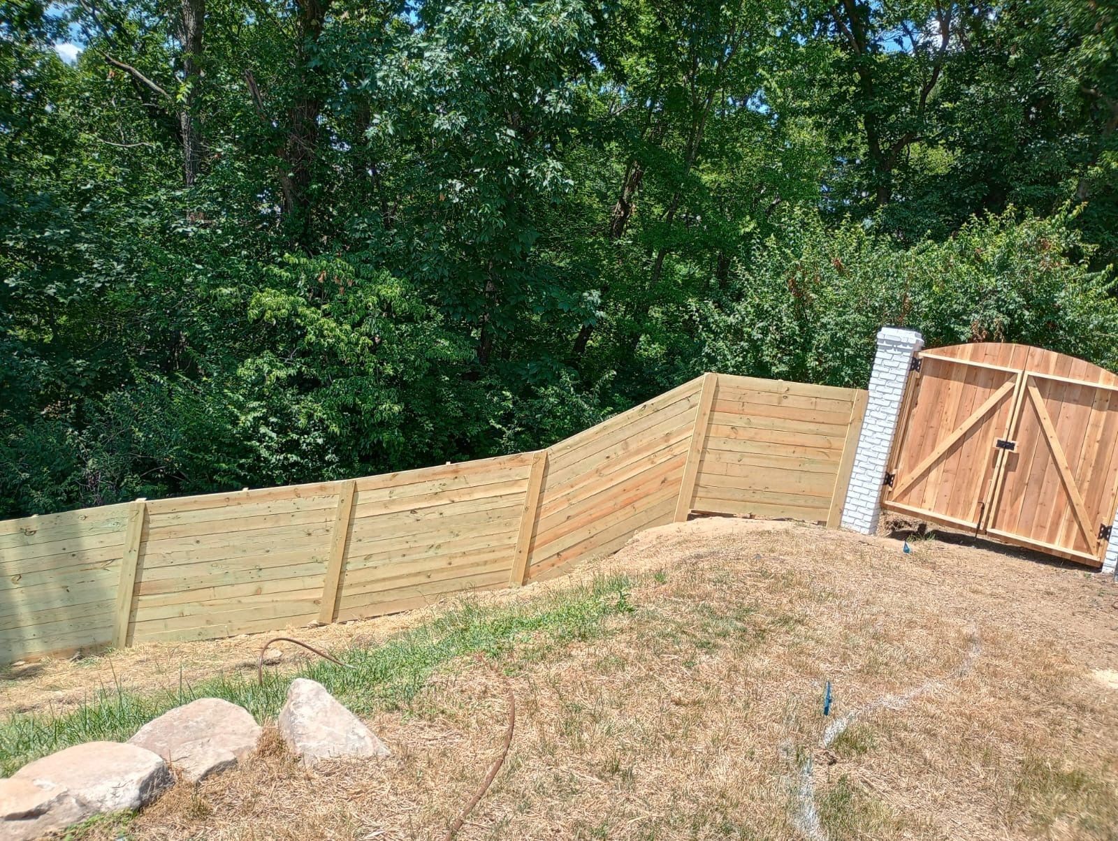 A wooden fence is sitting on top of a hill next to a wooden gate.