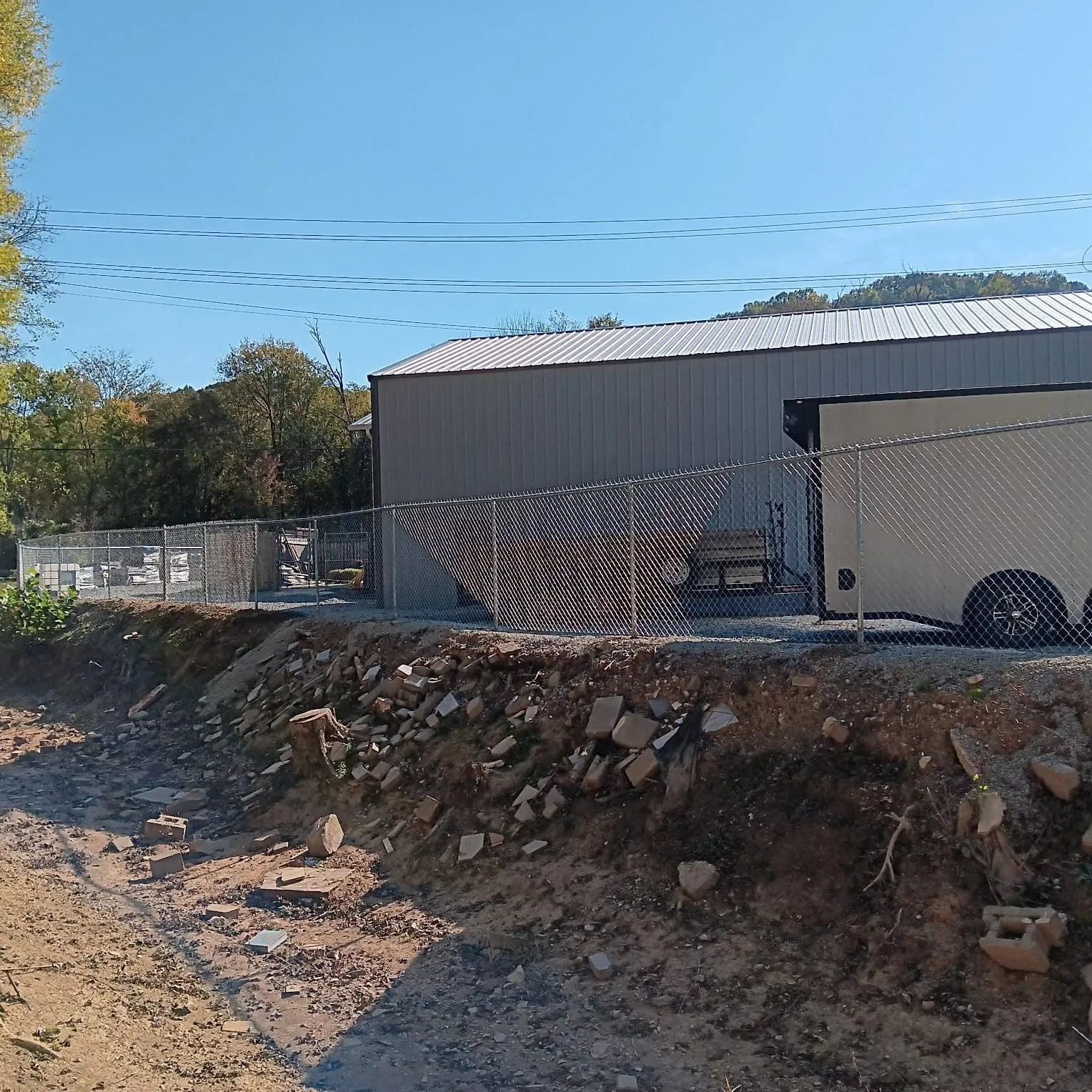 A trailer is parked in front of a building behind a chain link fence.