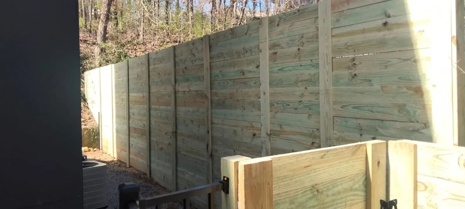 A wooden fence is being built in a backyard.