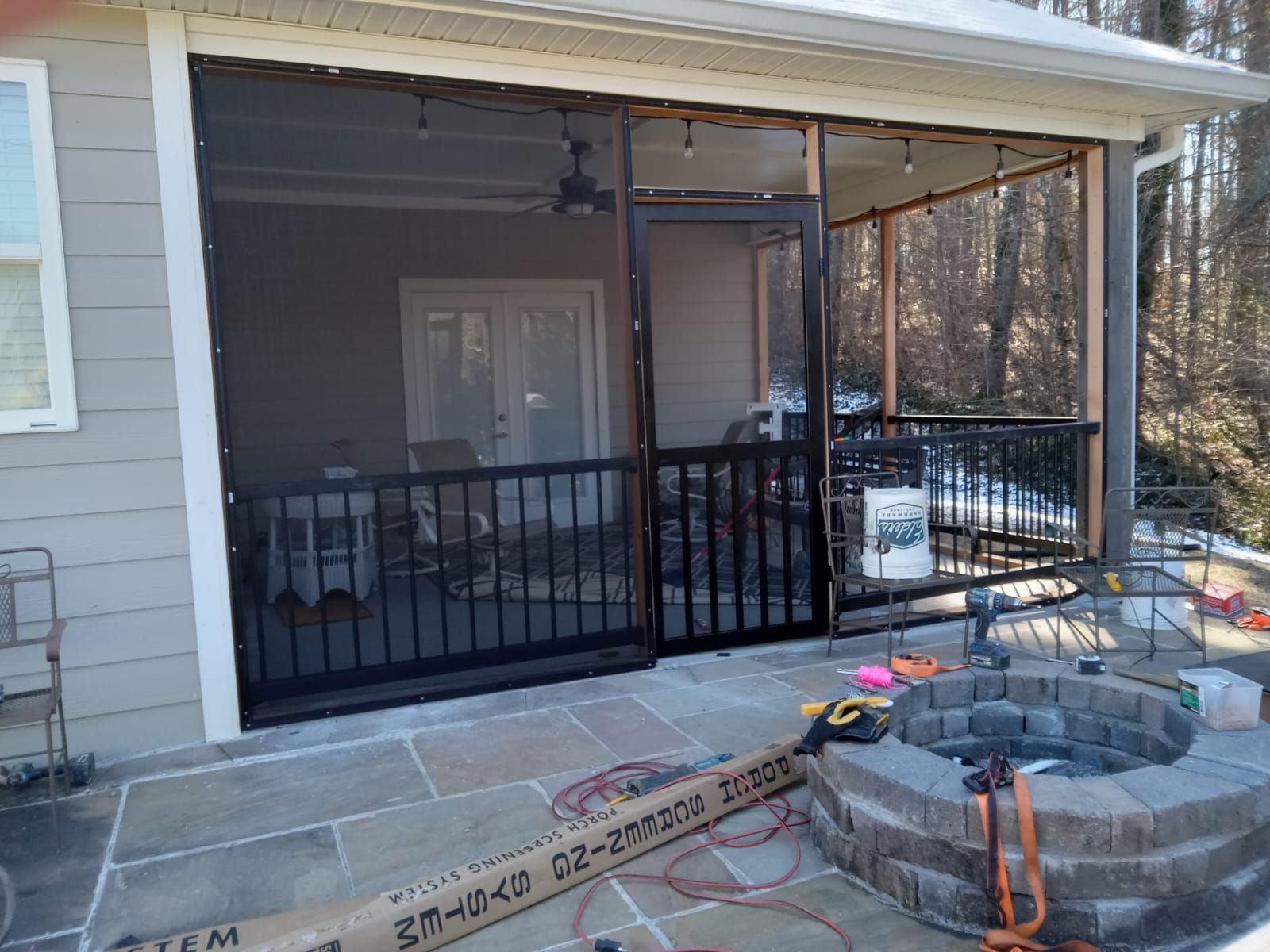A screened in porch with a fire pit in front of it.
