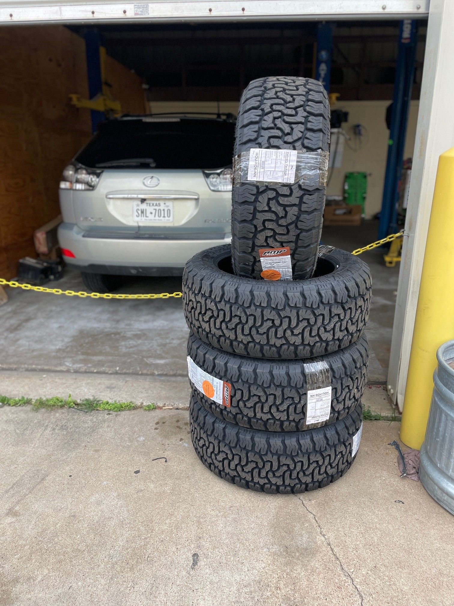 A bunch of tires are stacked on top of each other in a garage.