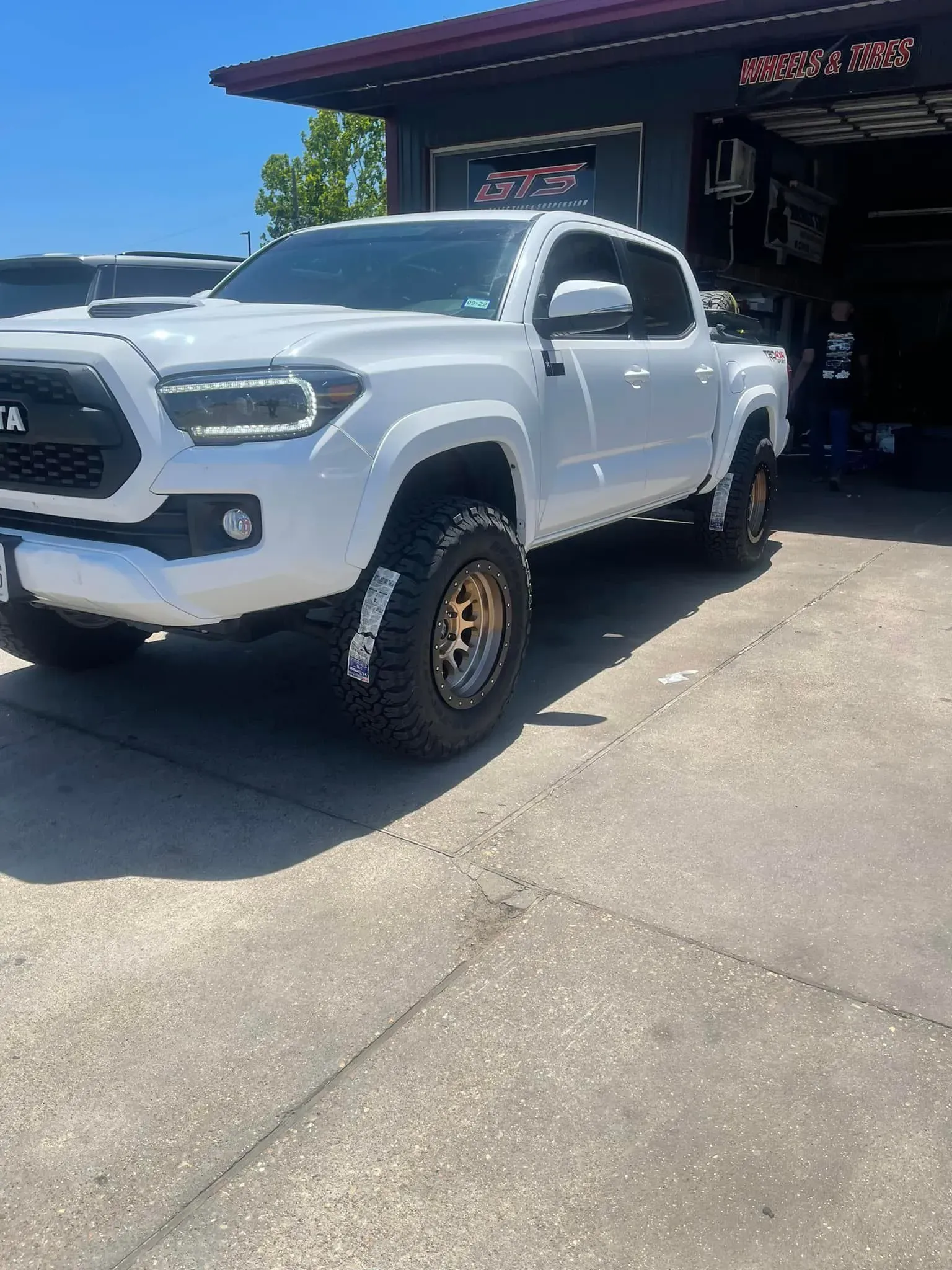 A white toyota tacoma truck is parked in front of a garage.