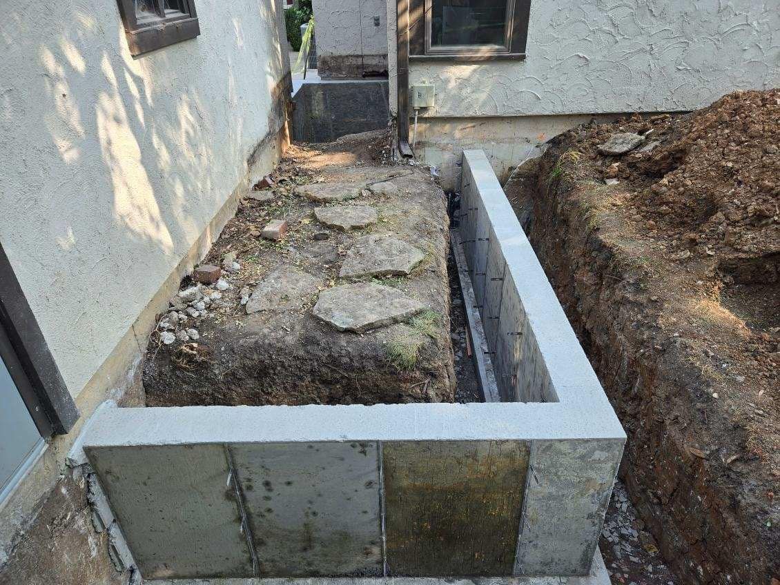 A concrete wall is being built in front of a house.