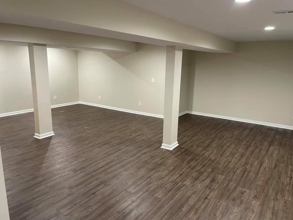 An empty basement with hardwood floors and columns.