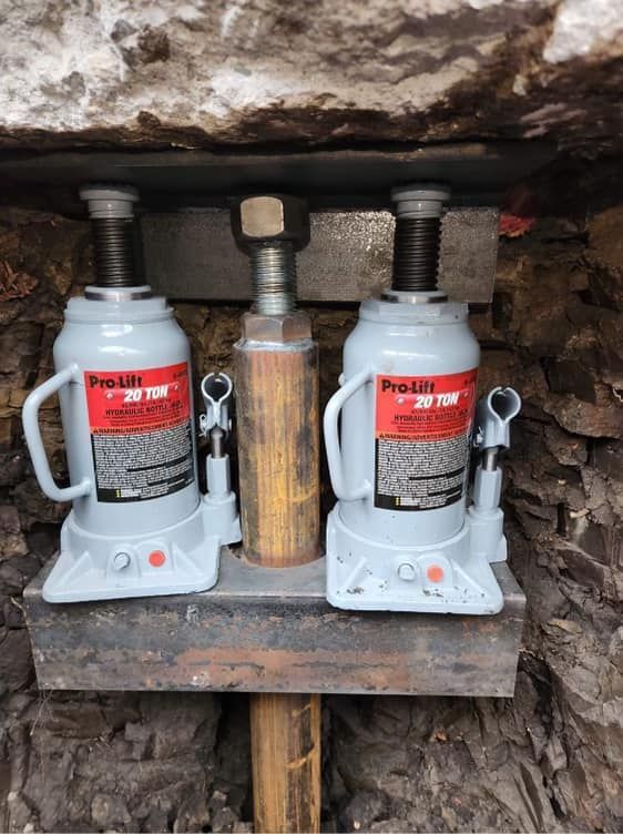 Two hydraulic bottle jacks are sitting on top of a wooden table.