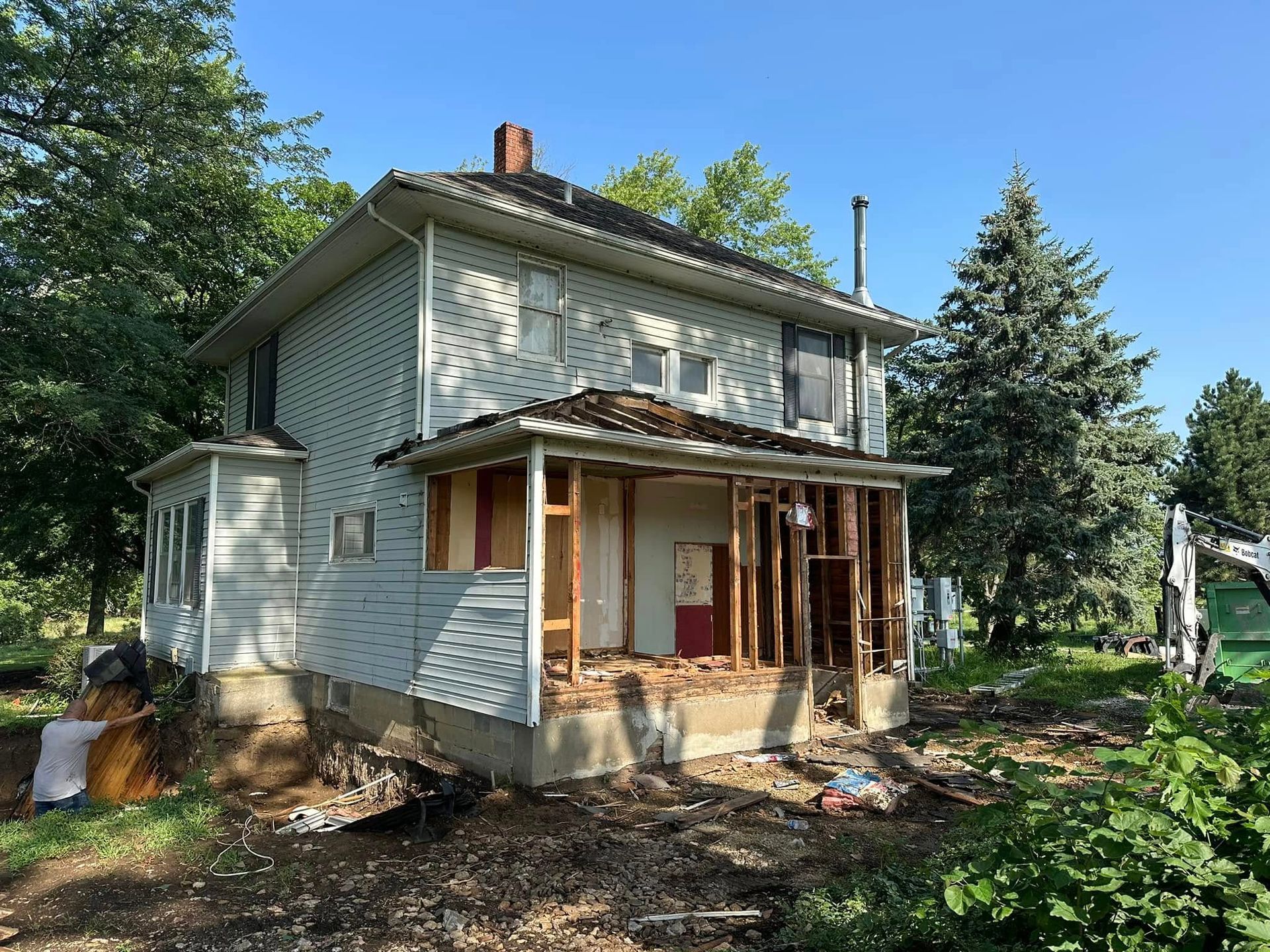 A white house with a porch is being demolished.
