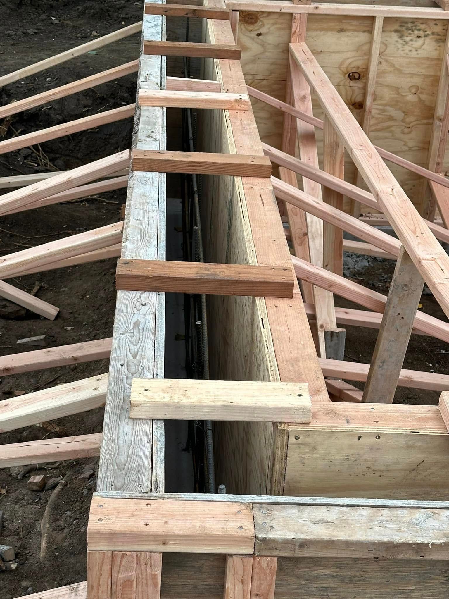 A wooden structure is being built on top of a dirt field.