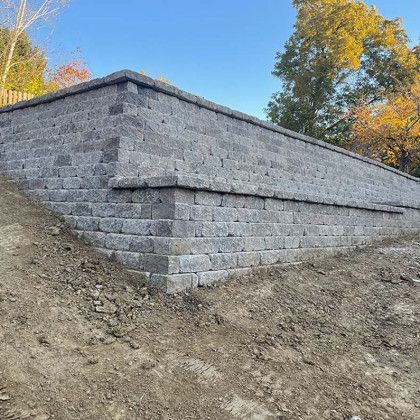 A large brick wall is sitting on top of a dirt hill.