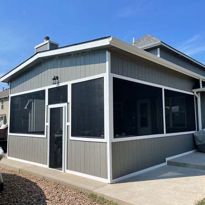 A house with a screened in porch and a car parked in front of it.