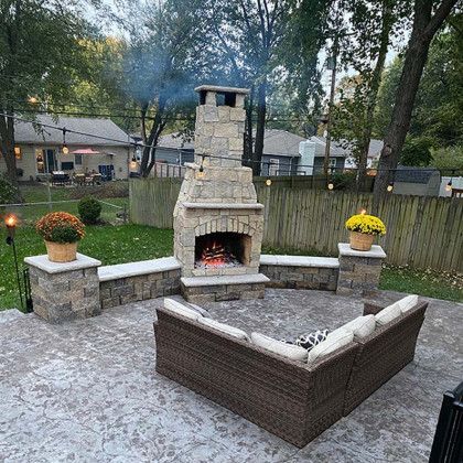 A patio with a fireplace and a couch in the middle of it.