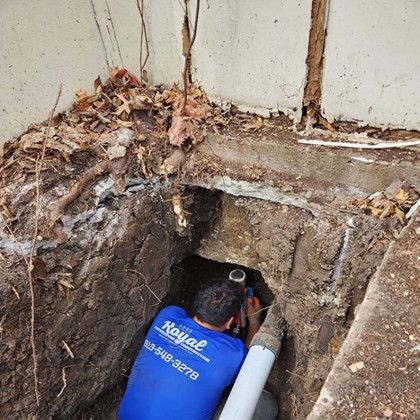 A man in a blue shirt is looking into a hole in the ground.