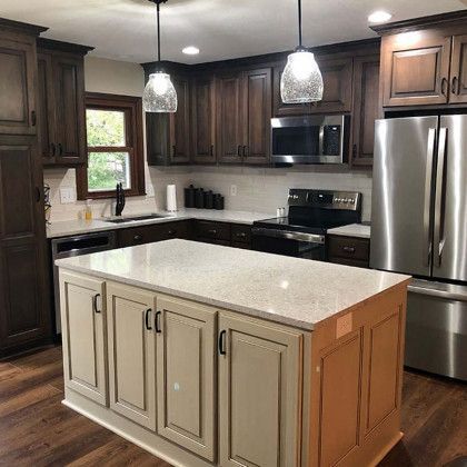 A kitchen with stainless steel appliances and a large island in the middle.