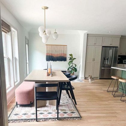 A dining room with a table and chairs and a dog in the background.