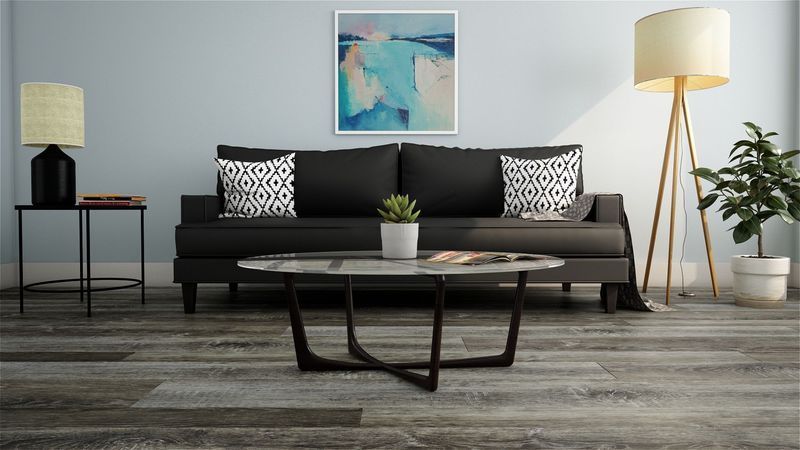 Living room with a black sofa, round coffee table, and abstract art on the wall.