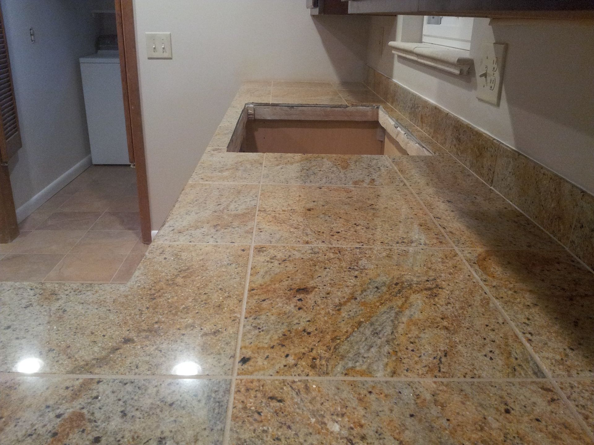 Granite countertop with a sink cutout. Beige, gold, and brown colors. Kitchen setting.