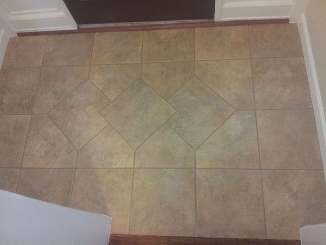 Tiled floor in a doorway; tan tiles form a central diamond pattern.