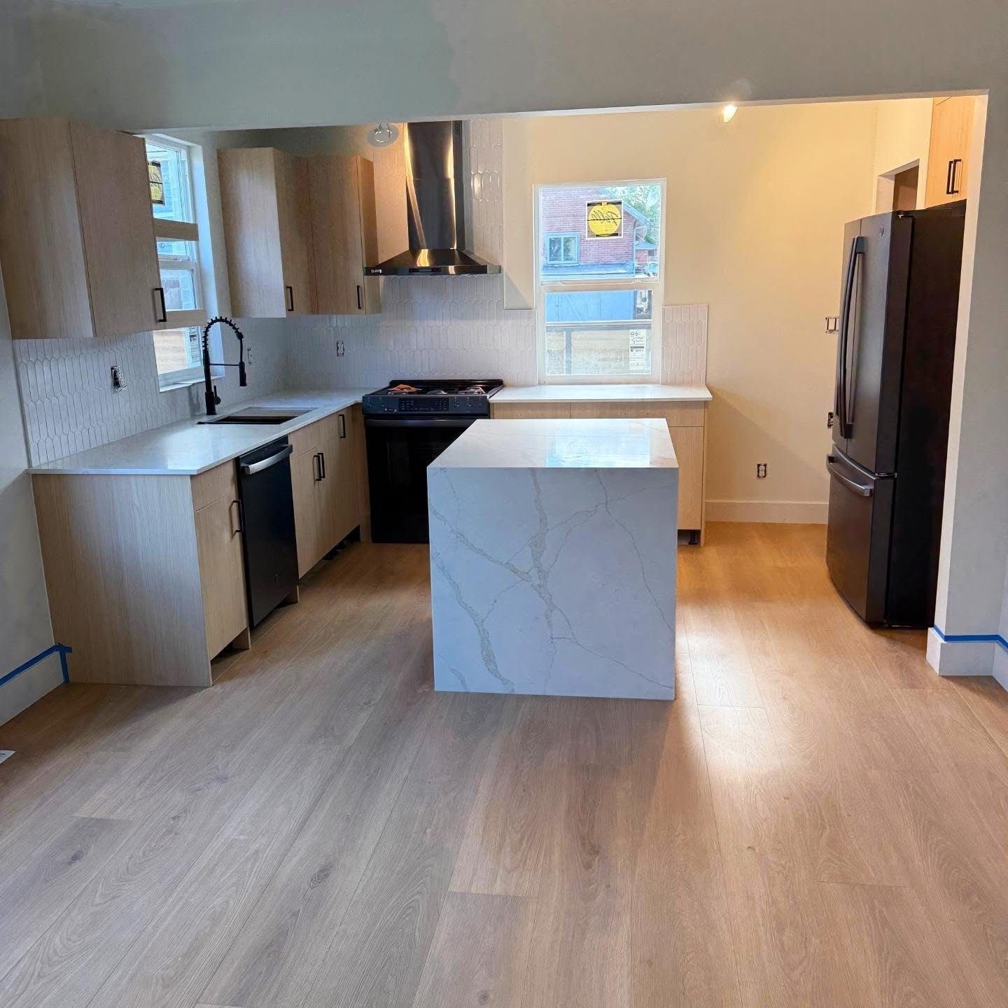 Modern kitchen with white cabinets, island, stainless appliances, and wood floors