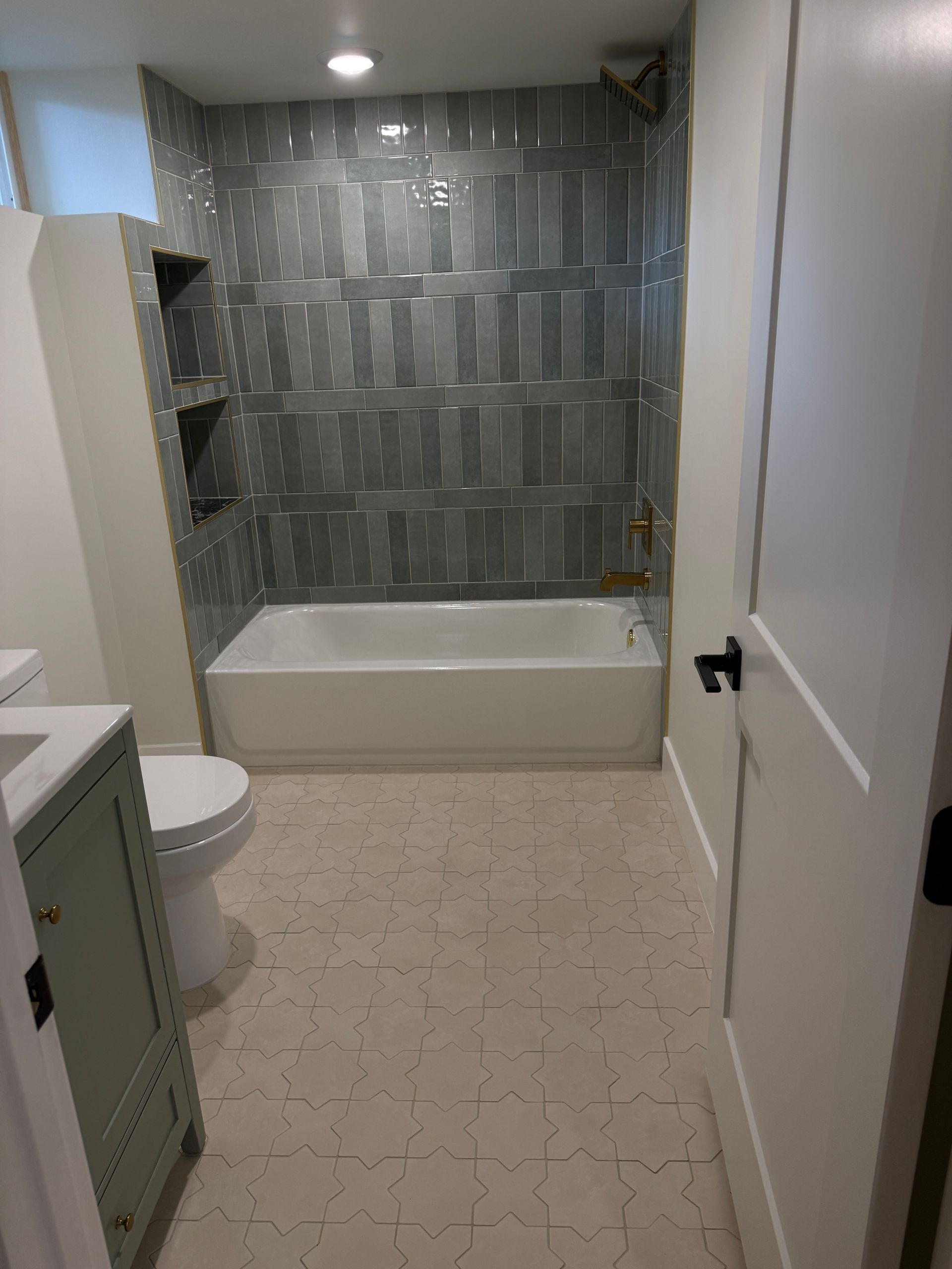 Modern bathroom with bathtub, glass tile shower wall, toilet, and vanity in view