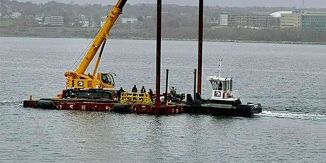 A yellow crane is sitting on top of a boat in the water.