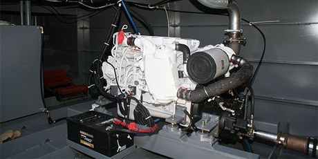 A large engine is sitting in the engine room of a boat.