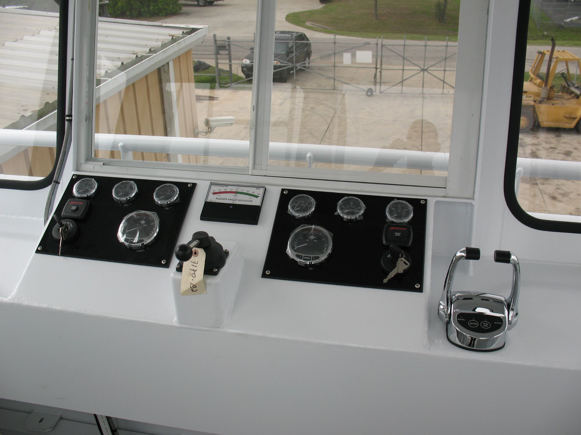 A control panel on a boat with a forklift in the background