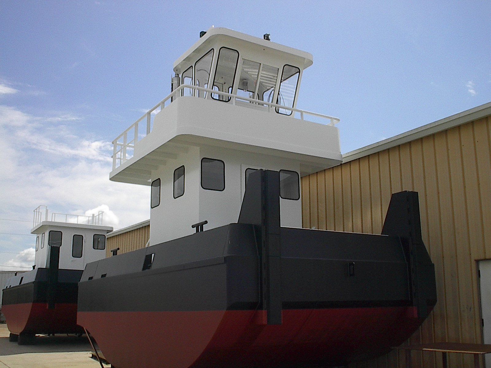 A boat with a tower on top of it is parked in front of a building.