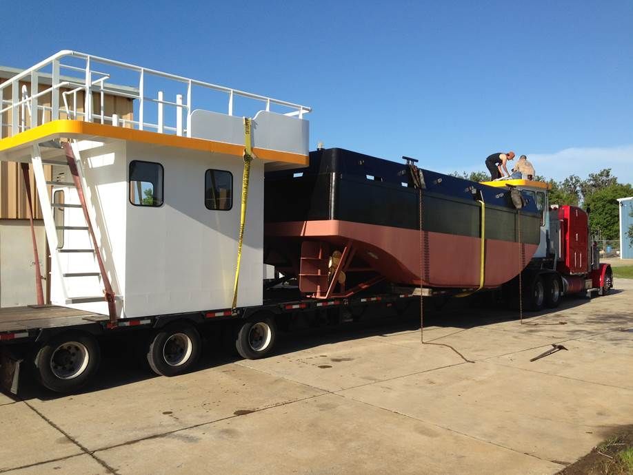 A large boat is being transported by a semi truck