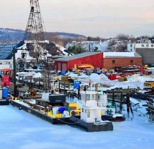 Several boats are docked in a snowy harbor