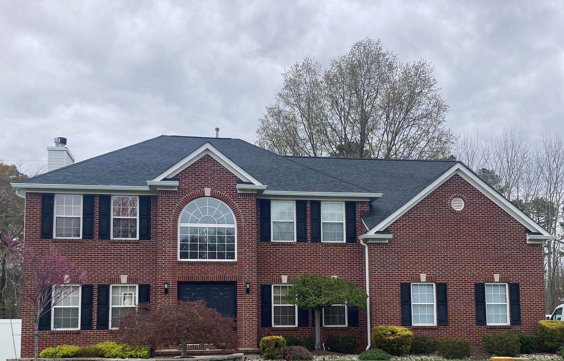A large brick house with a black roof and black shutters