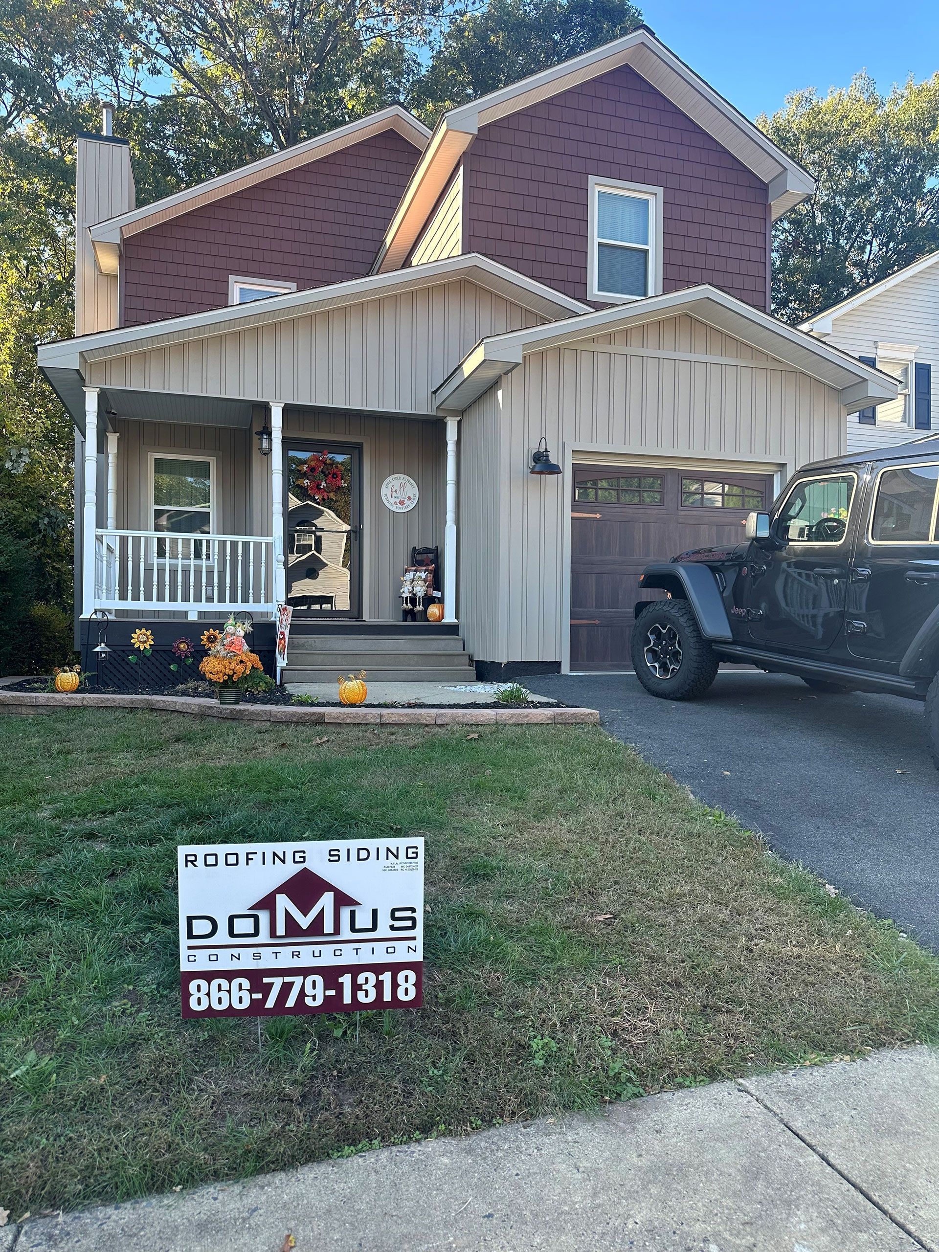A jeep is parked in front of a house with a sign in front of it