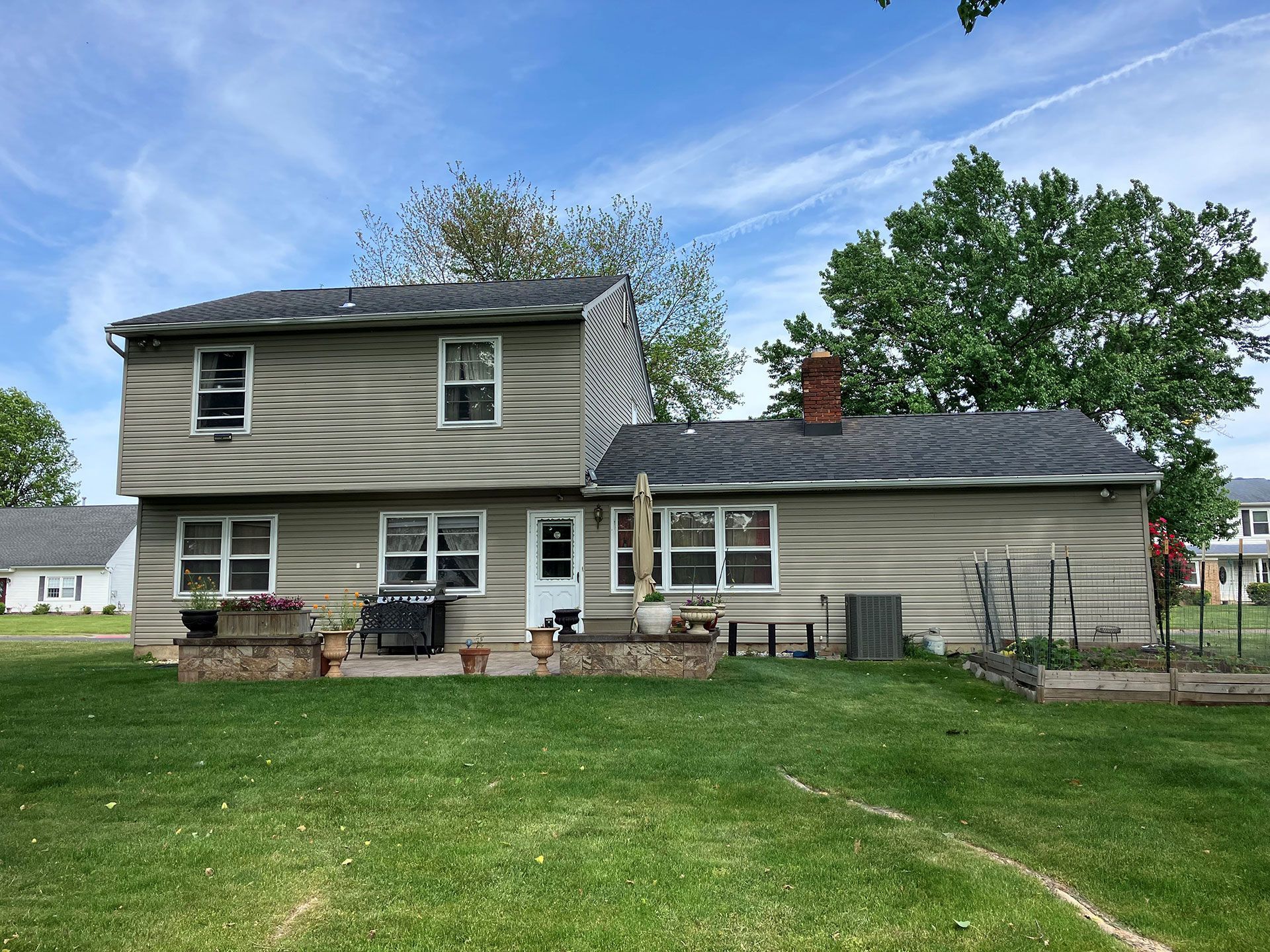 The back of a house with a large lawn in front of it.