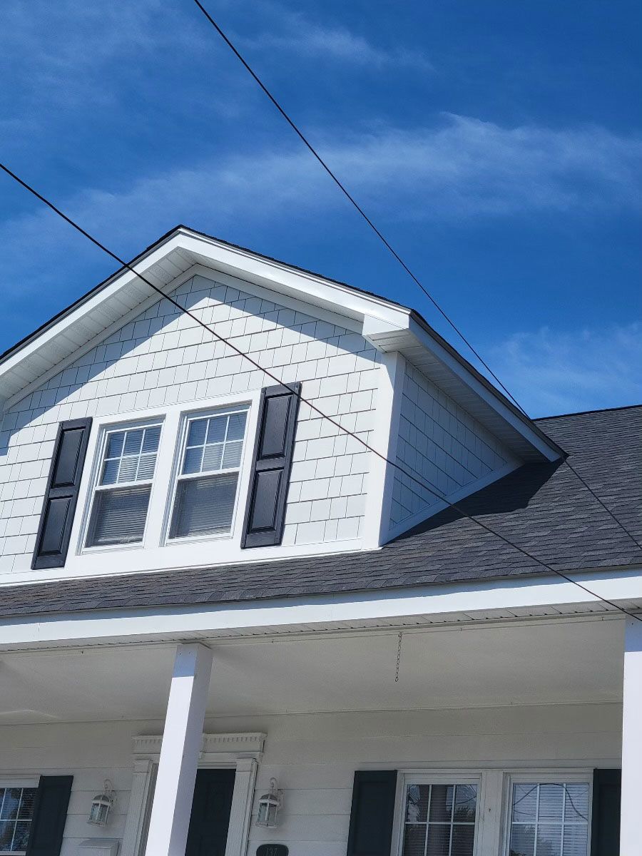 A white house with black shutters and a blue sky in the background