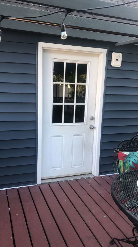 A white door is sitting on a wooden deck next to a blue house