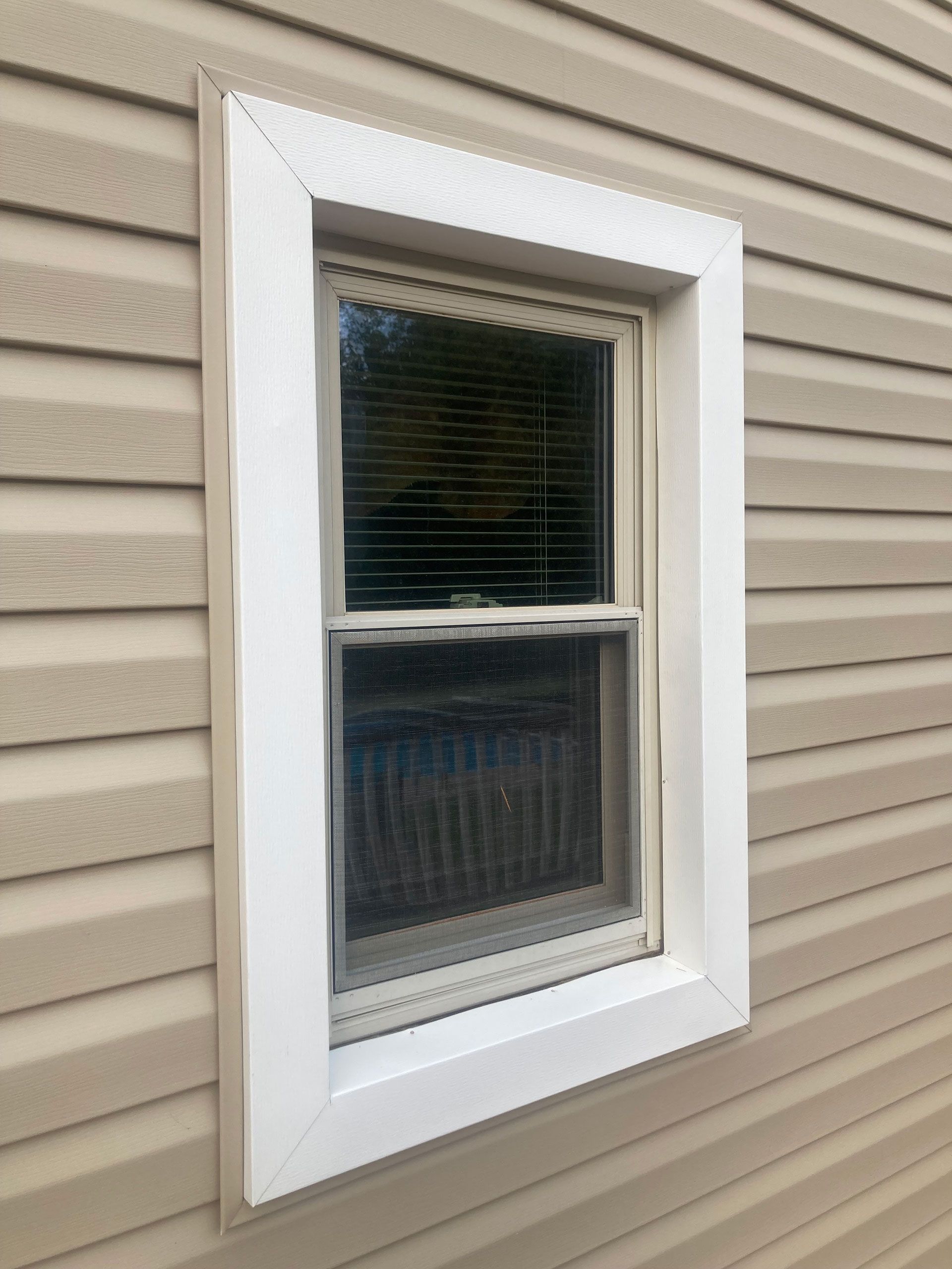 A window on the side of a house with a white frame