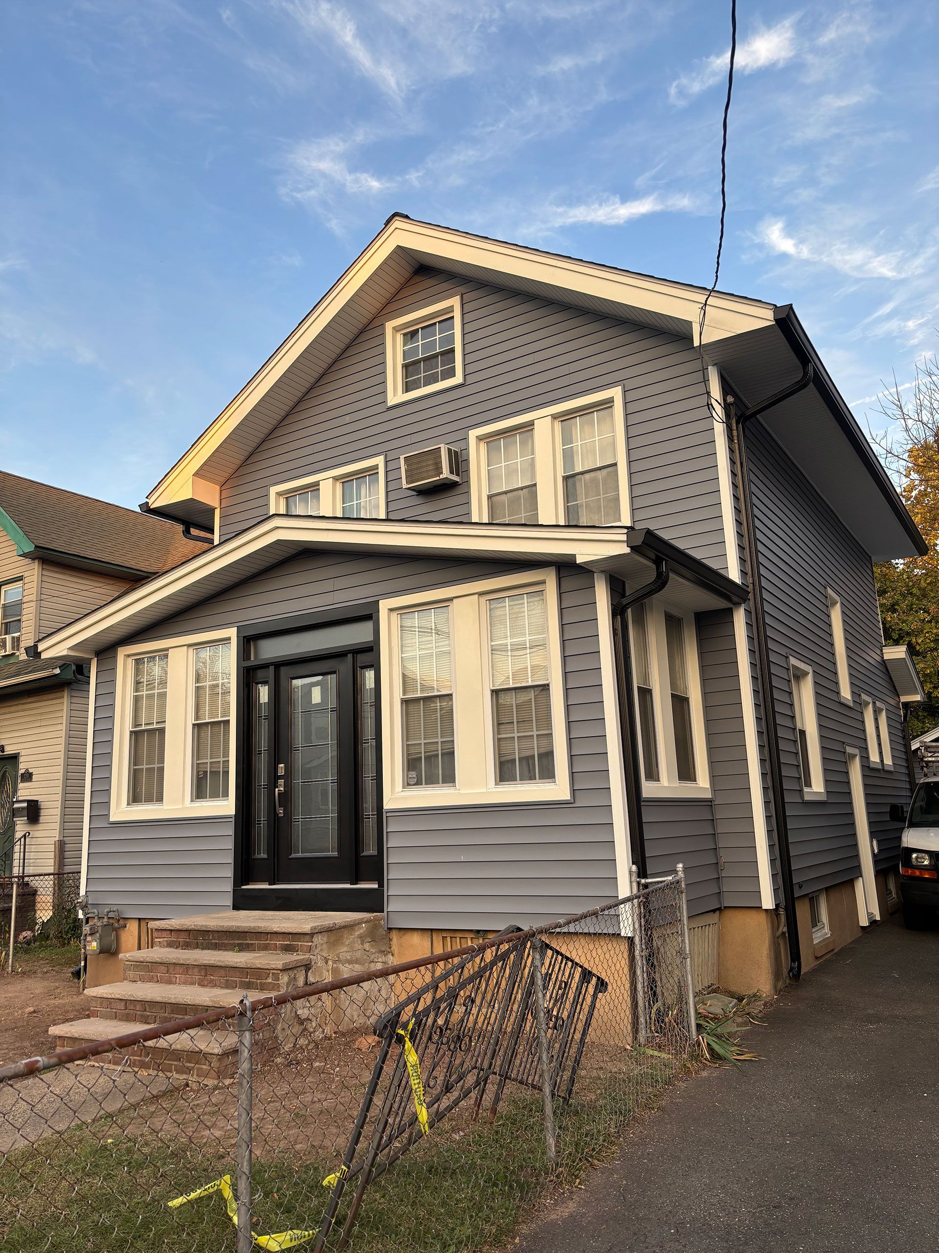 A gray house with white trim and a black door