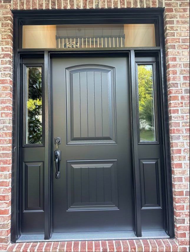 A black door with a brick wall behind it