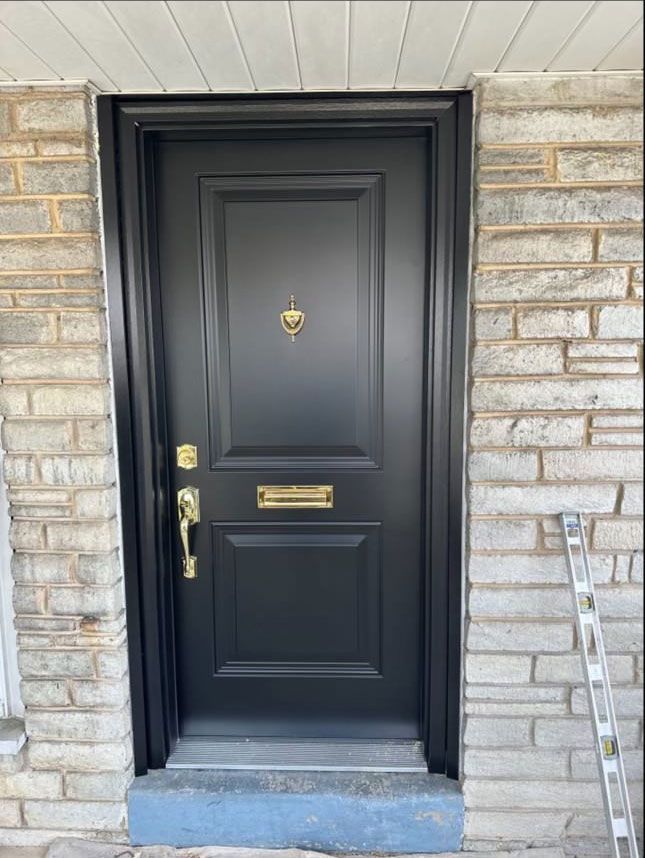 A black door is on a brick wall next to a ladder