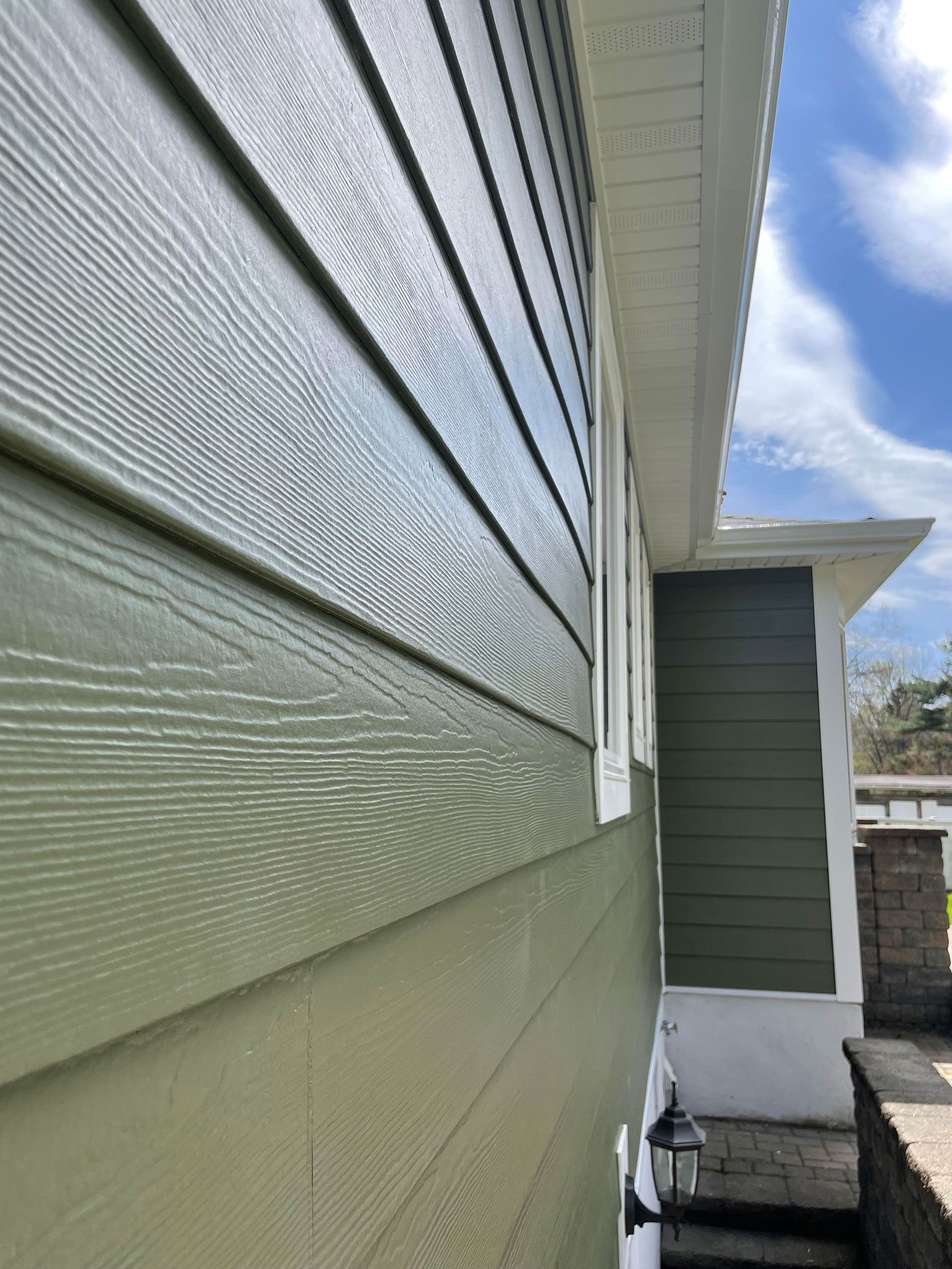 The side of a house with green siding and a window