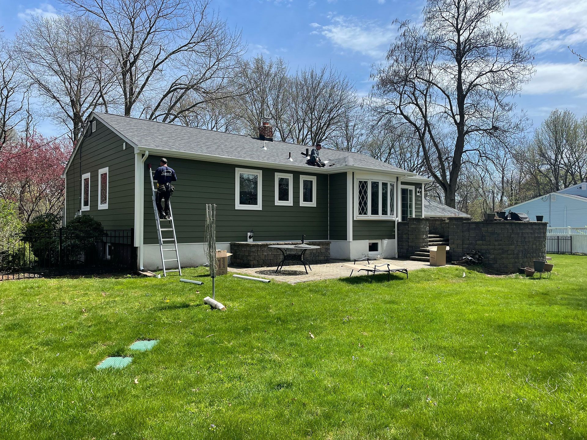 A man is standing on a ladder in front of a house