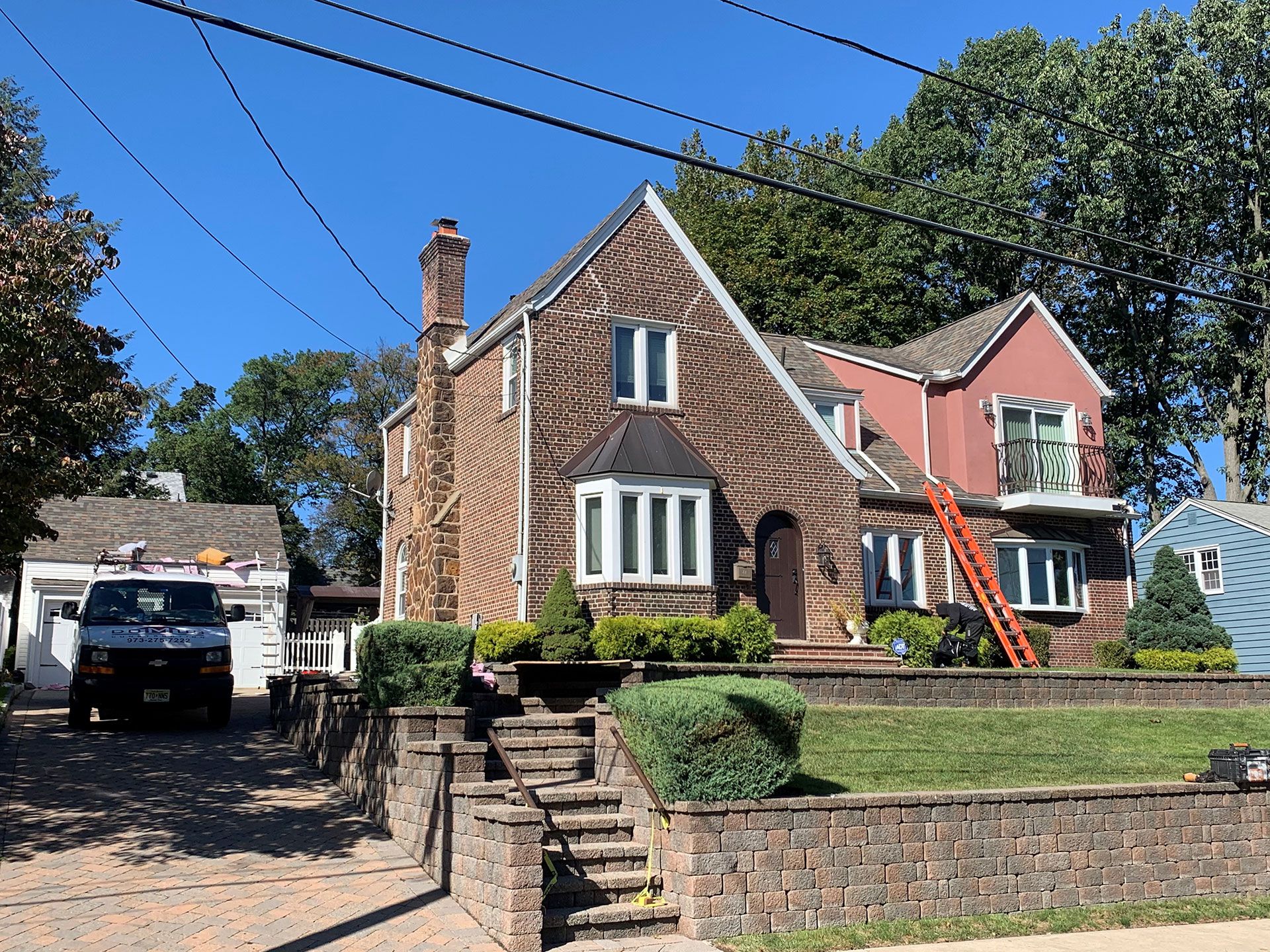 A white van is parked in front of a large brick house