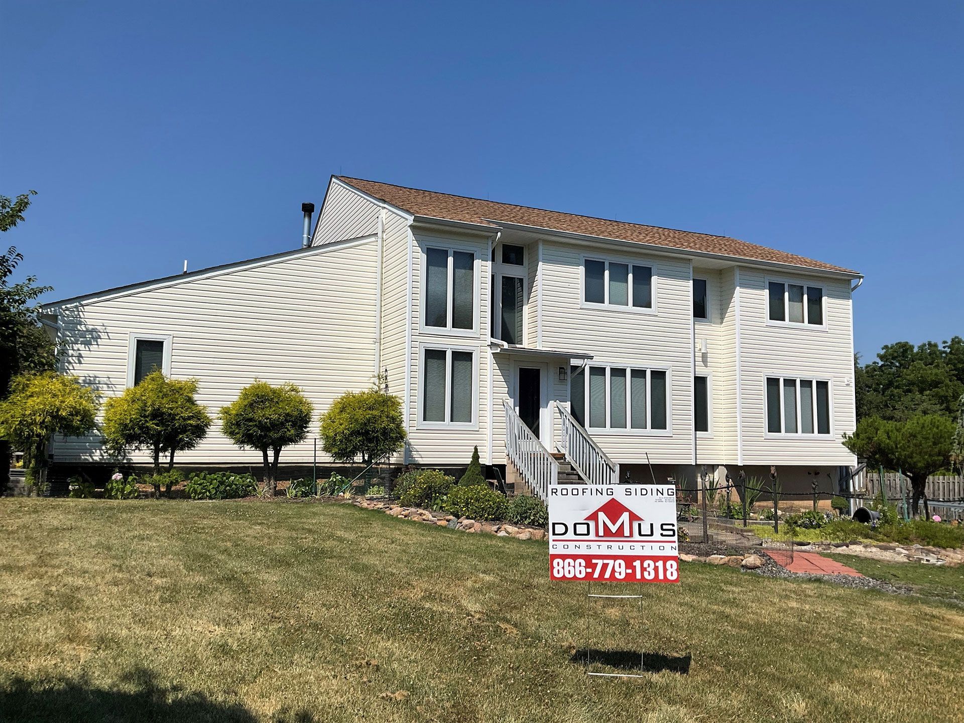 A large white house with a for sale sign in front of it