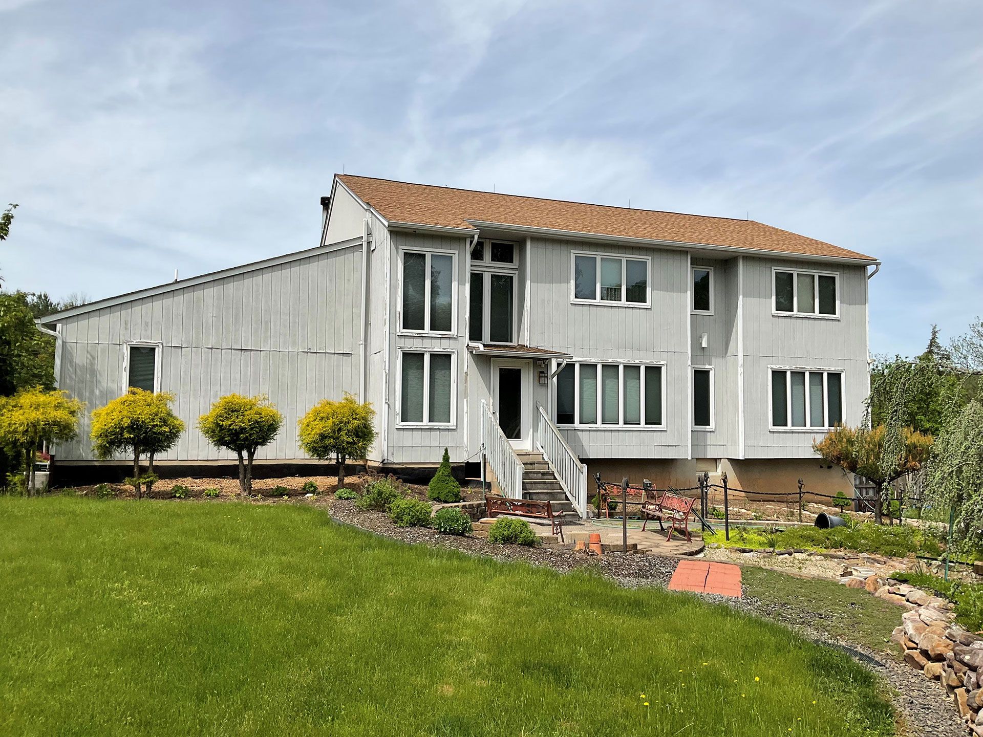 A large white house with a brown roof is sitting on top of a lush green hillside