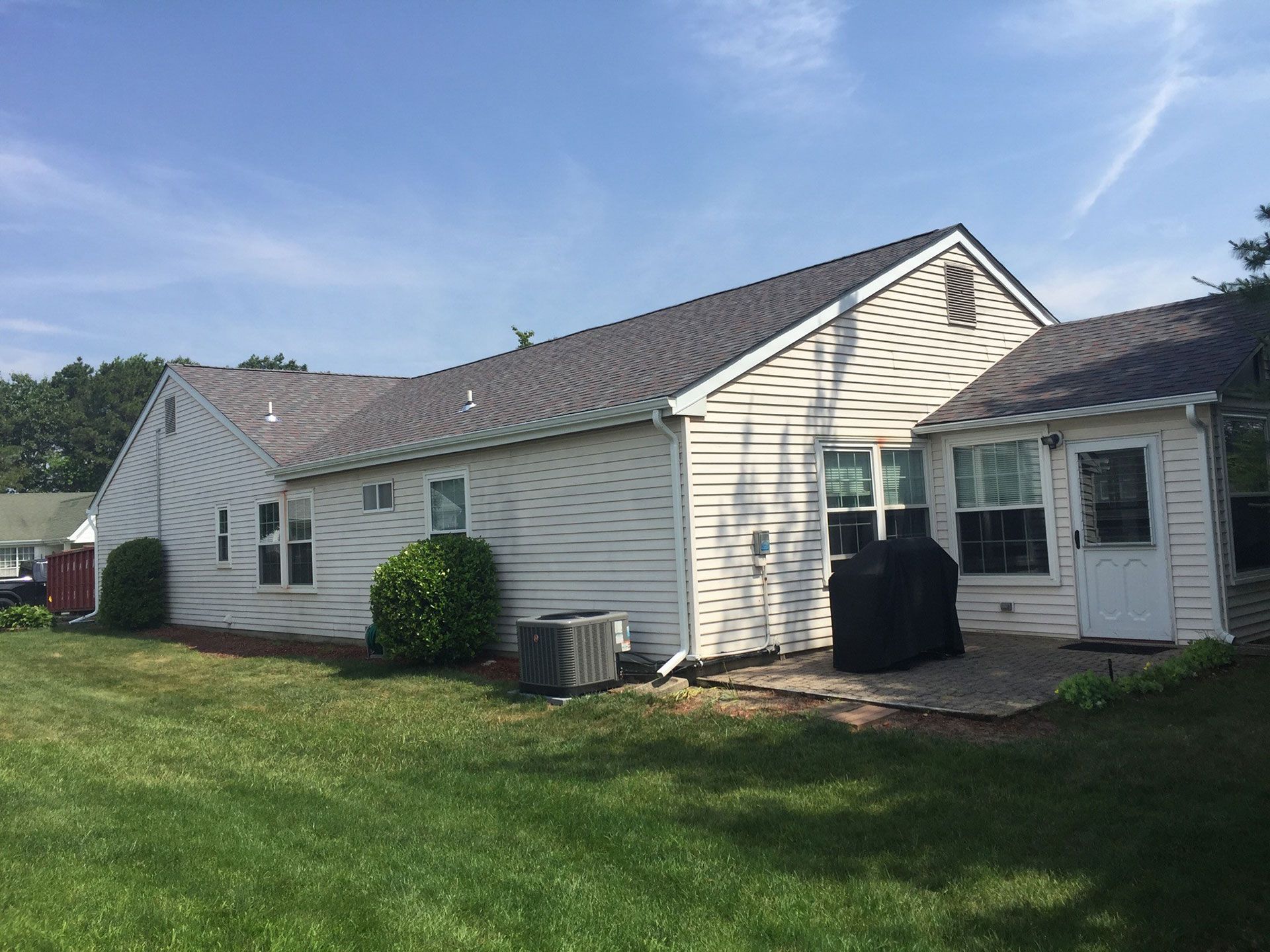A white house with a gray roof is sitting on top of a lush green lawn