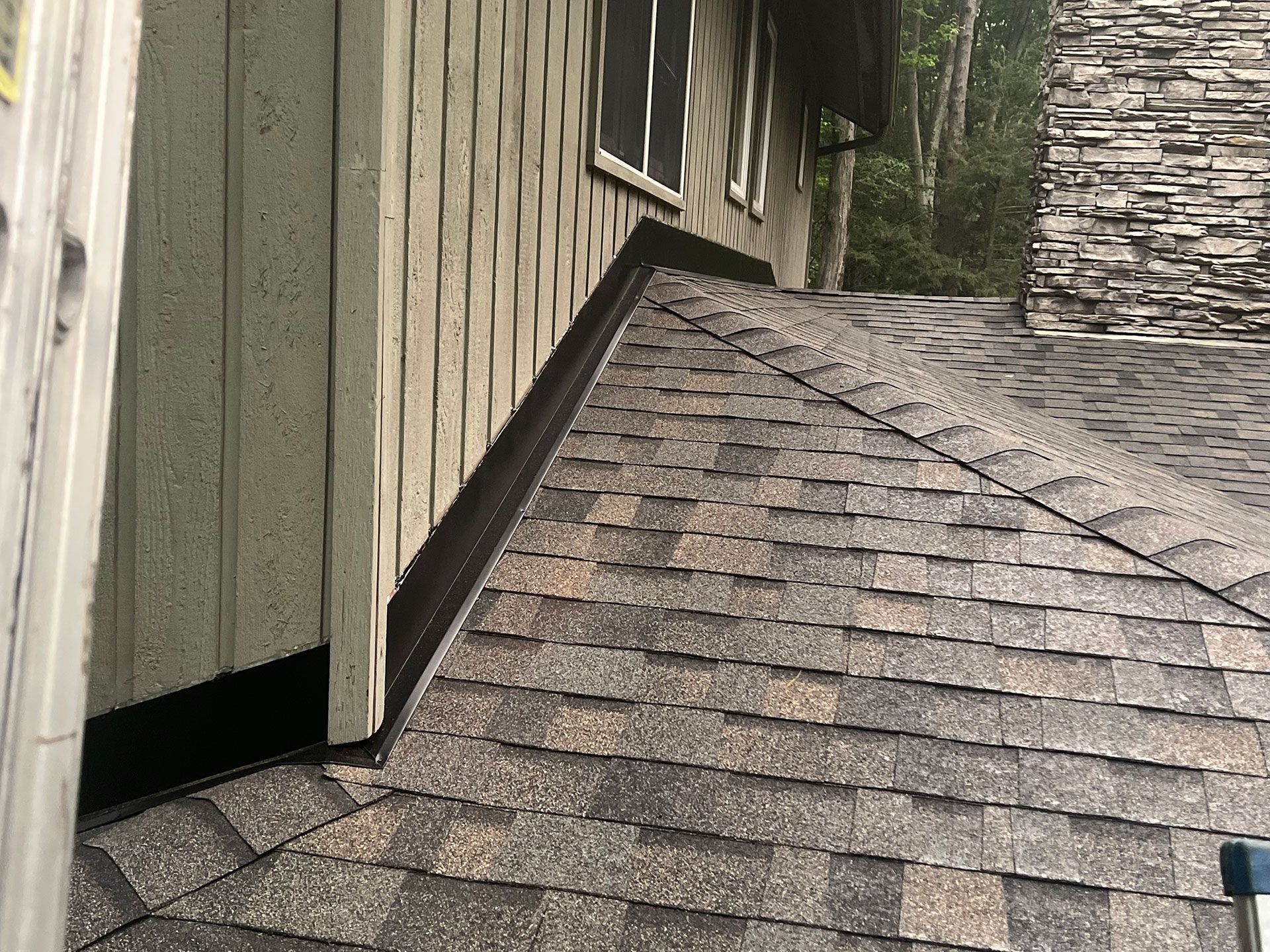 A ladder is sitting on the side of a house next to a roof