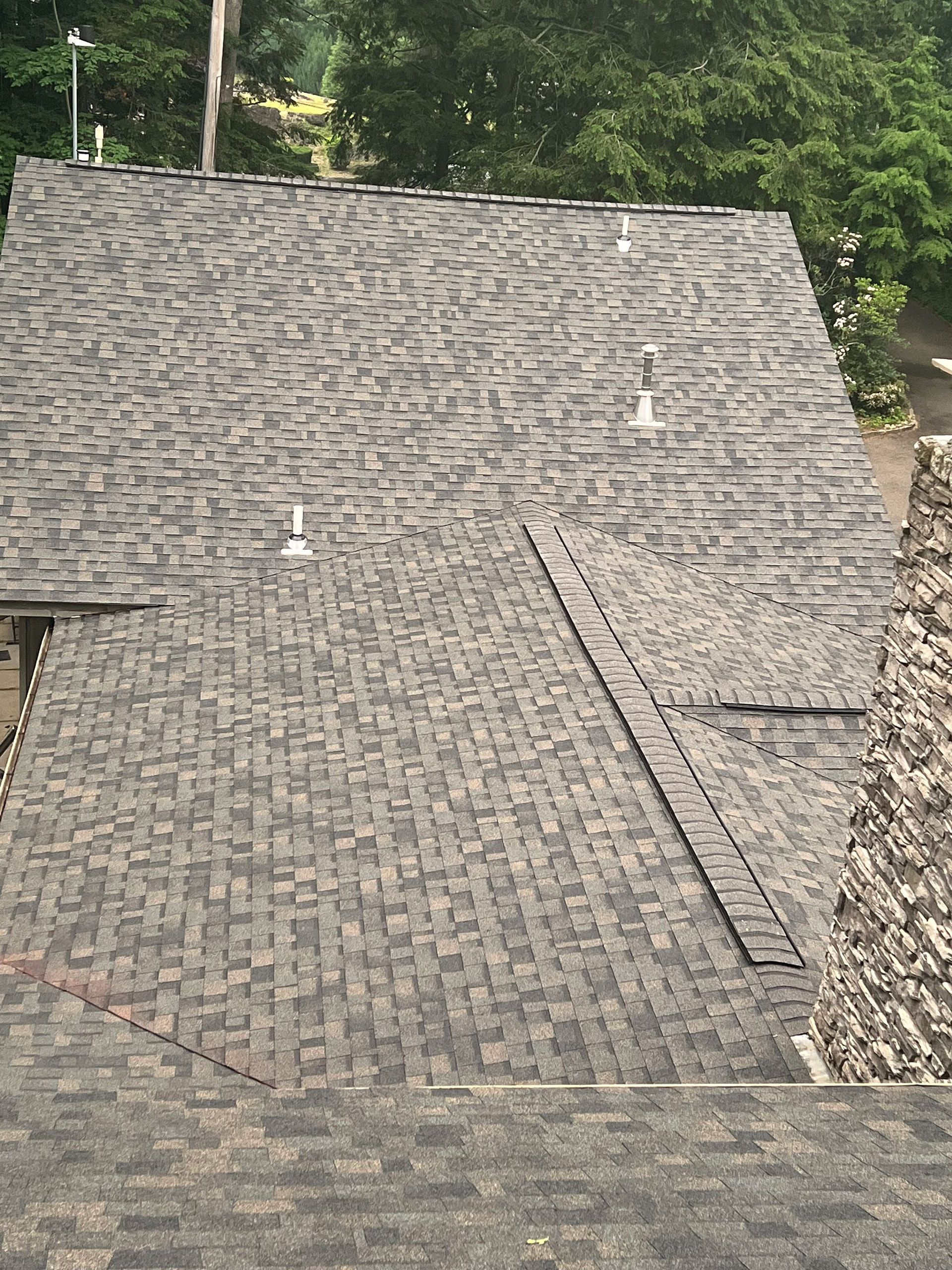 A roof with a lot of shingles on it and trees in the background