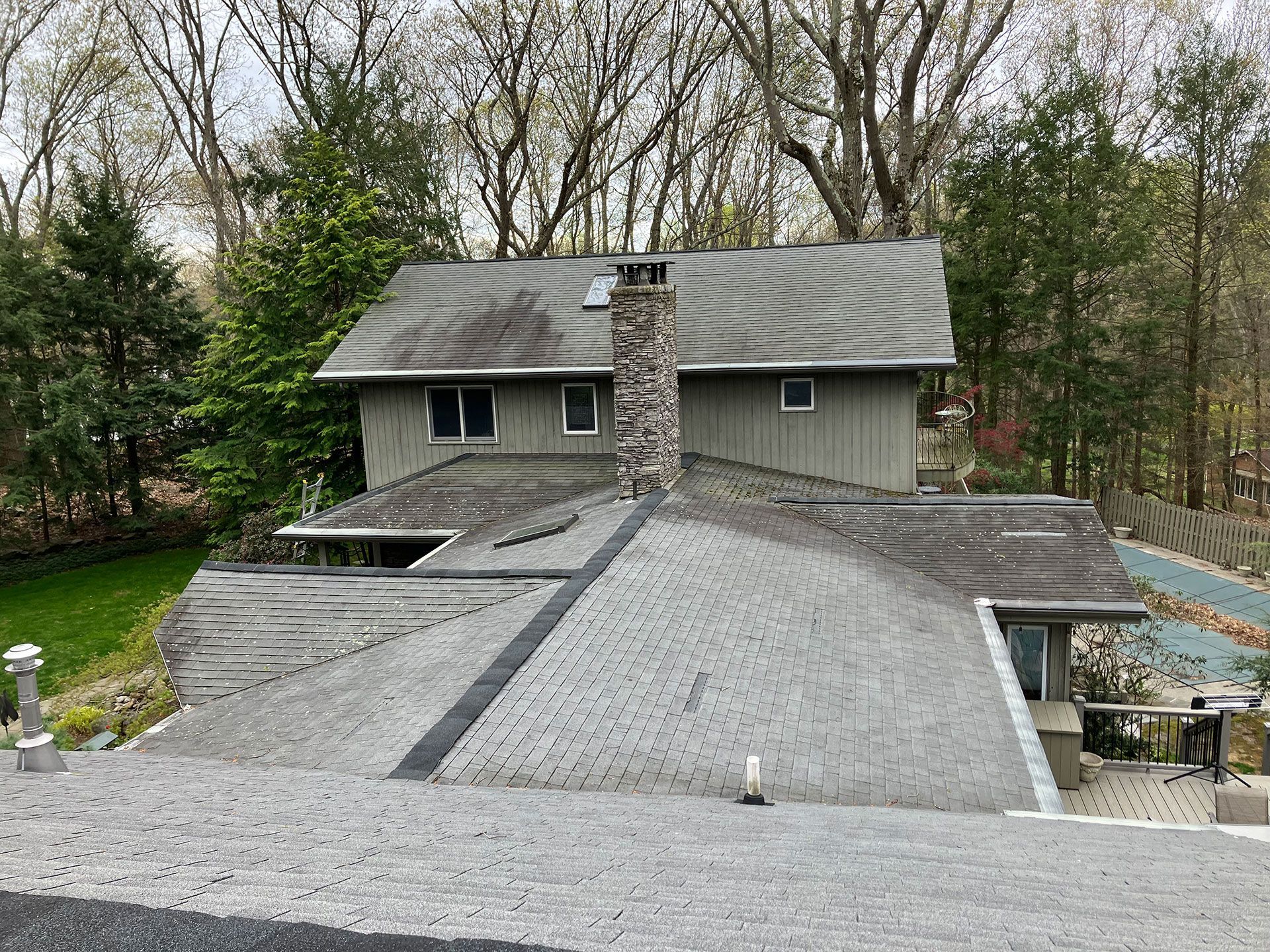 The roof of a house with a chimney and trees in the background