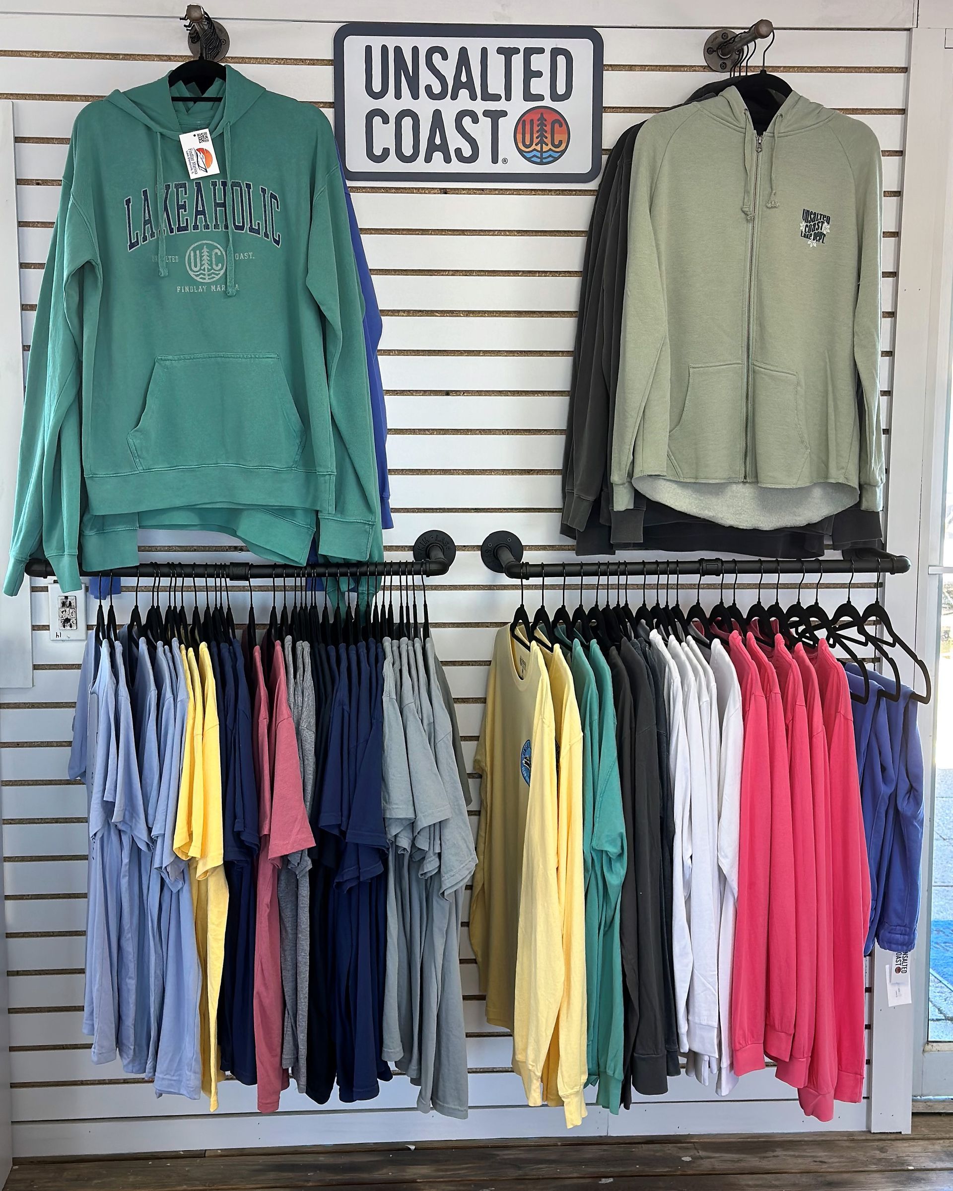 Clothing display in a retail store with hoodies and t-shirts in various colors on racks