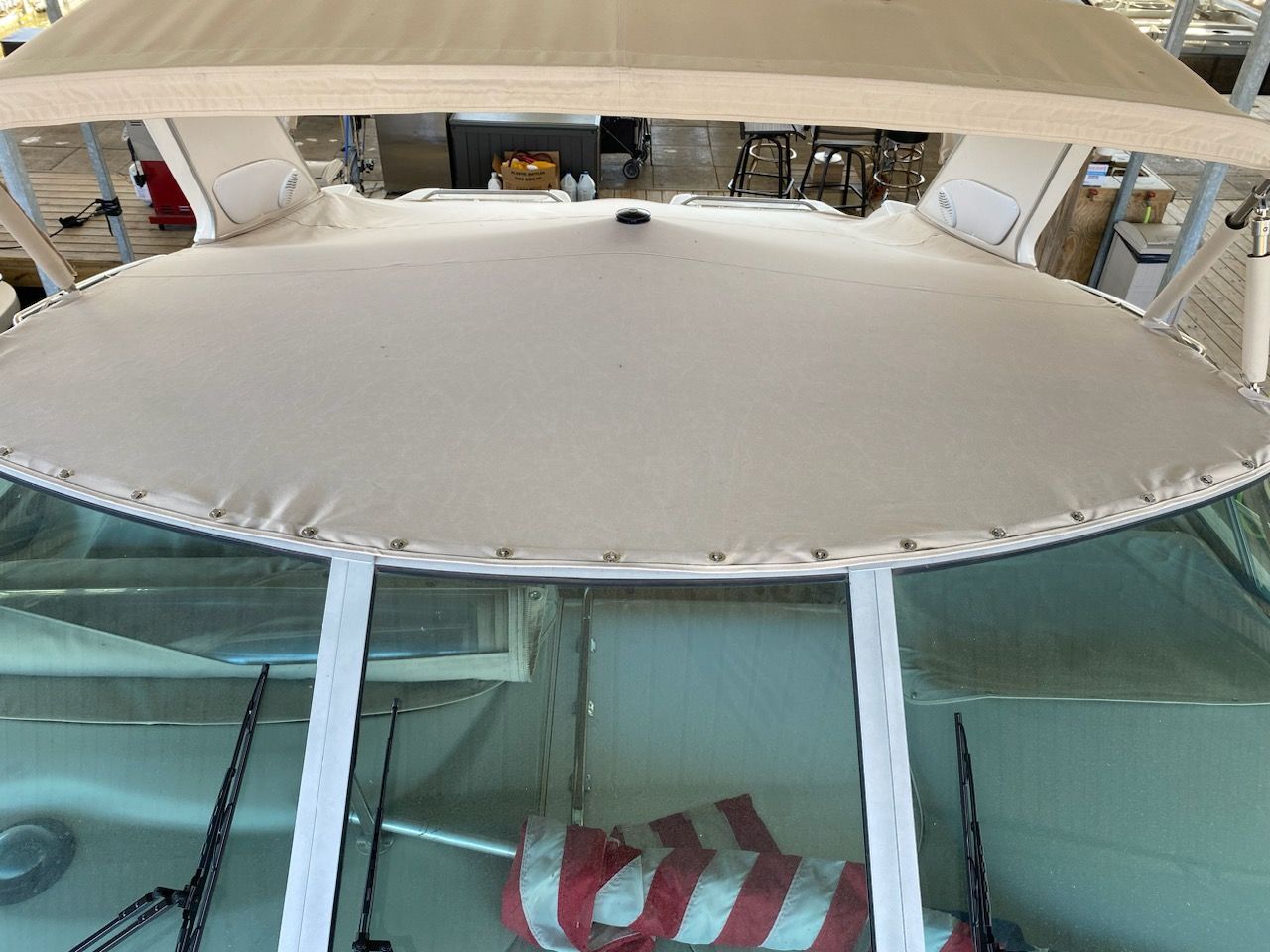 Tan boat cabin top with windshield and American flag.